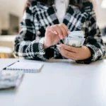 Karyawan menghitung uang tunai di lingkungan kantor, menggambarkan proses perhitungan gaji bersih atau take home pay